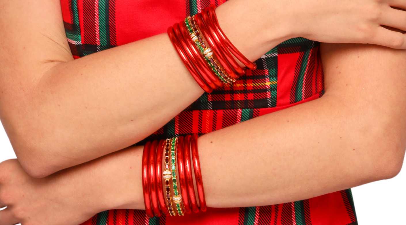 Woman in plaid holiday dress wearing BuDhaGirl Crimson All Weather Bangles And BuDhaGirl's Aurora Crystal bracelet in Emerald and Ruby | BuDhaBrief by BuDhaGirl