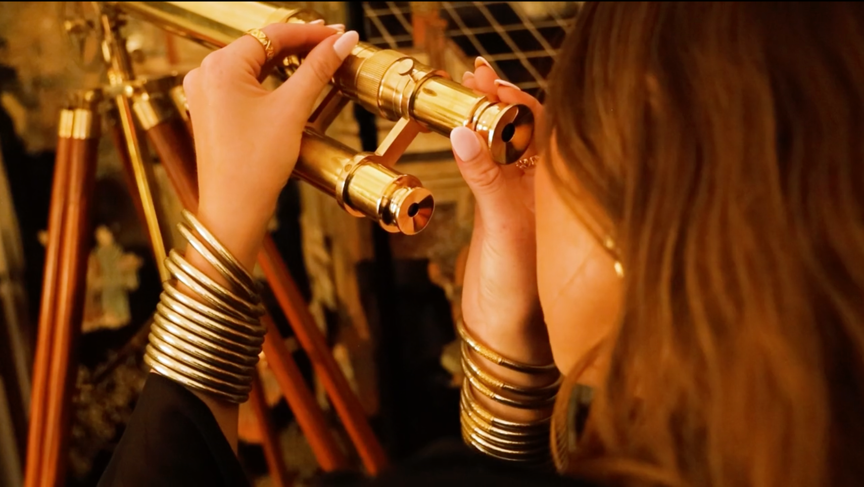 Woman Wearing Etoile All Weather Bangle Bracelets Looking Through Gold Telescope | BuDhaGirl